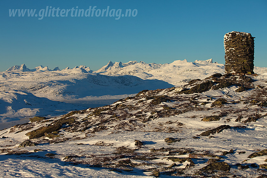 Varden på toppen av Målegge (1454 moh) med Hurrungane bl.a. i bakgrunnen. Man ser også en flik av det islagte Tyin.