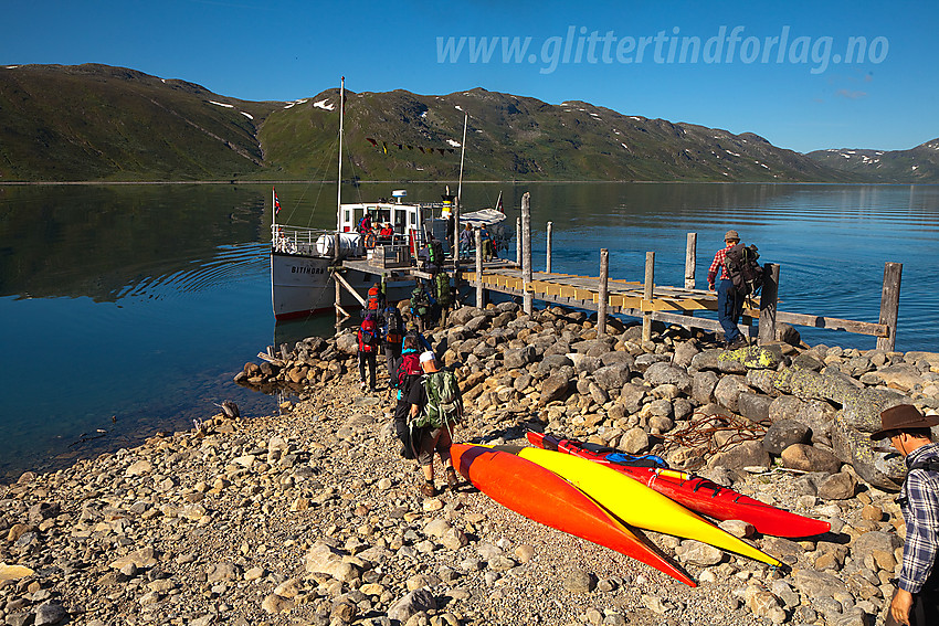 Passasjerer går ombord i M/B Bitihorn ved brygga på Torfinnsbu en flott sommermorgen.