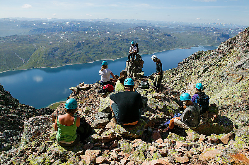 Pause på et markert fremspring som deler "normalrenna" til Øystre Torfinnstinden i to. I bakgrunnen Bygdin, Skjeldrane, Vølohornet, Vølodalen og Dryllenøse, samt fjell og vann så langt øye kan se.