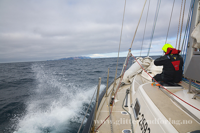 På overfarten Island - Jan Mayen med seilbåt. Etter 3 døgn til havs dukker omsider Jan Mayen opp i det fjerne. Og det beste av alt: Hele Beerenbergvulkanen er å se.