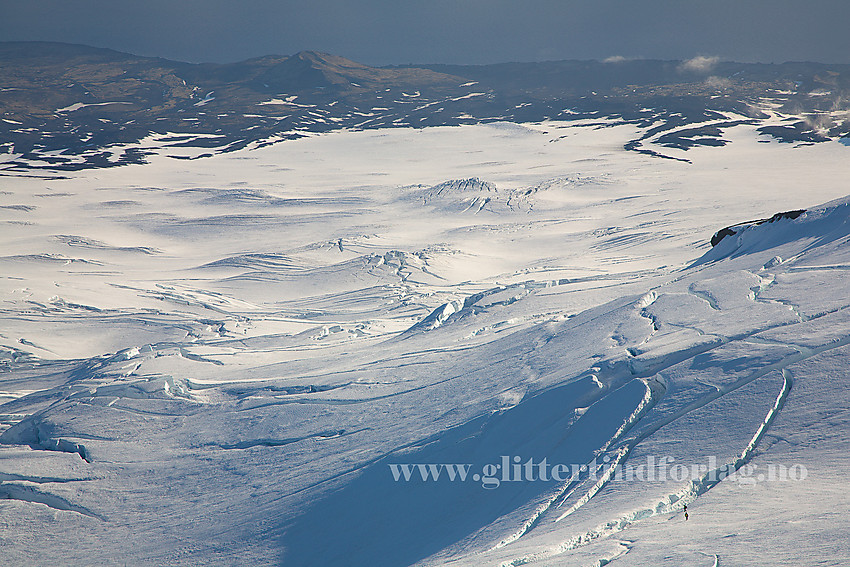 Fra Bratthenget på Beerenberg mot Kerckhoffbreen. Toppen ut mot kysten i bakgrunnen er Krossberget. Legg merke til to brevandrere nede til høyre på bilde. De blir små i forhold til sprekkene.