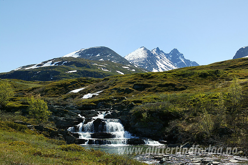 Ved broa over Helgedalselvi like ved Turtagrø med det kjente panoramaet bestående av Nørdre, Midtre og Store Skagastølstinden, i bakgrunnen.