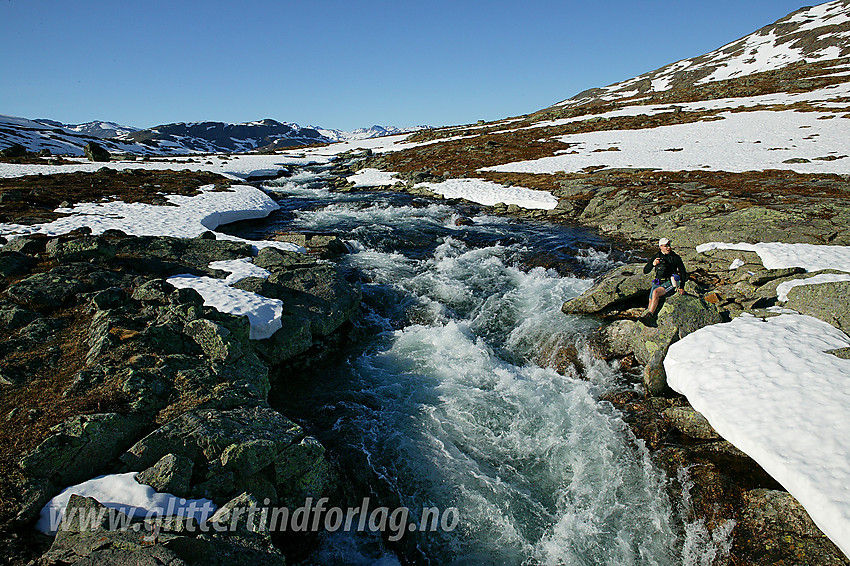 Fra hengebroa over Høystakka med elva dundrende skumhvit nedenunder og Jotunheimens snøfjell i bakgrunnen.