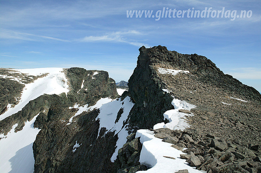 Like vest for Slettmarkpiggen mot toppen. Toppen ligger luftig til, nærmest oppå et fremspring til venstre. Man ser også personer oppe ved toppen. I bakgrunnen til venstre ses Slettmarkhøe.