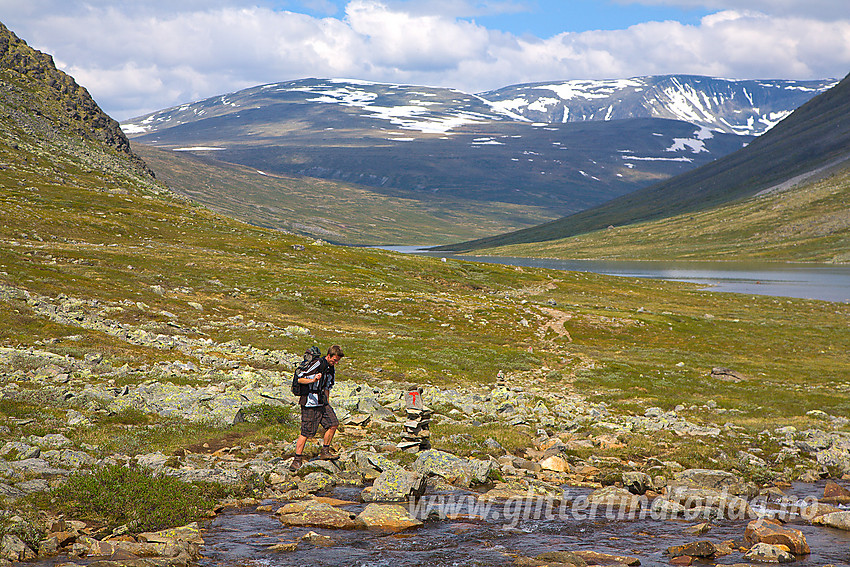 Fjellvandrer på vei sørover mot Memurubu på ruta fra Glitterheim. I bakgrunnen bl.a. Russvatnet, Austre Hestlægerhøe og Nautgardsoksle.