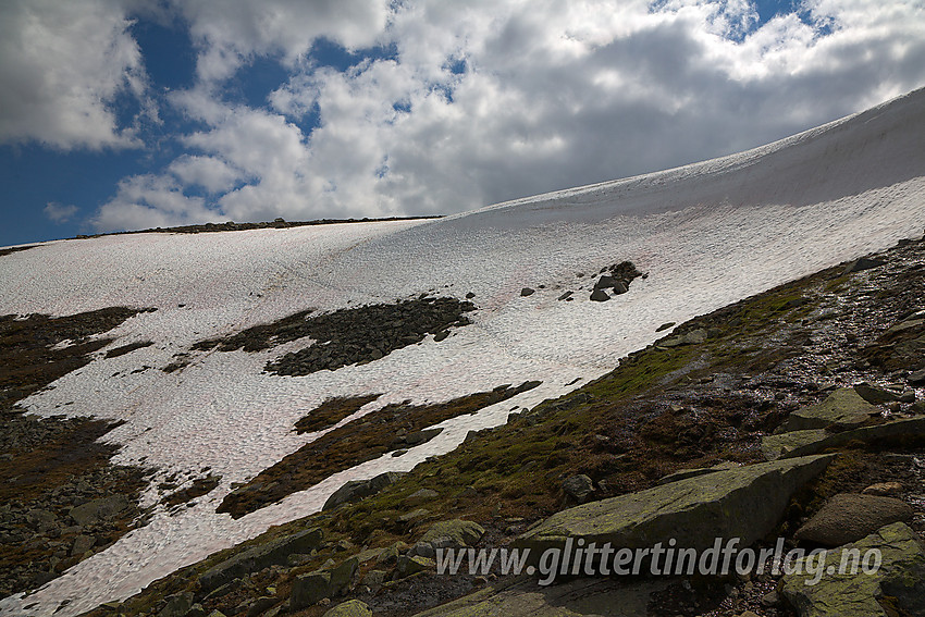 På vei opp fra Nedre Russglopet mot fjellryggen ovenfor Gjende, på ruta fra Glitterheim mot Memurubu. I snørike somre ligger det en bratt og solid snøfonn her hvor den merkede stien går. Man blir derfor tvunget til å gå lenger til venstre (øst) inntil den har smeltet noe ned. Normalt ikke noe problem, men kan være en liten utfordring i dårlig sikt andre veien når merkingen leder rett utfor en skavlkant.