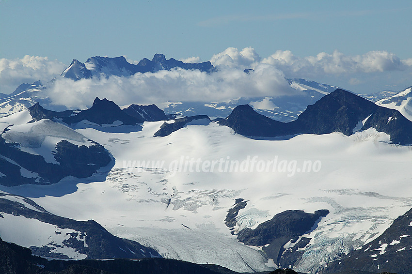 Fra toppen av Galdhøpiggen (2469 moh.) med telelinsa mot Storebrean med Smørstabbtindane rundt (fra høyre mot venstre): Store Smørstabbtinden (2208 moh.), Kniven (2133 moh), Sauen (2077 moh.), Skeie (2118 moh.), Sokse (2189 moh.) og Veslebjørn (2150 moh.), med Geite (2002 moh) foran. I bakgrunnen reiser Styggedals- og Skagastølsryggen seg. Fra venstre til høyre ses: Gjertvasstinden (2351 moh.), Store Styggedalstinden med Vest- (2377 moh.) og Østtoppen (2387 moh.), Sentraltinden (2348 moh.), Store Skagastølstinden (2405 moh.), Vetle Skagastølstinden (2340 moh.) og Midtre Skagastølstinden (2284 moh.) med V-skardet tydelig synlig til høyre for denne. Skagastølsnebbet (2222 moh.) og Nørdre Skagastølstinden (2164 moh) blir borte i skyene.