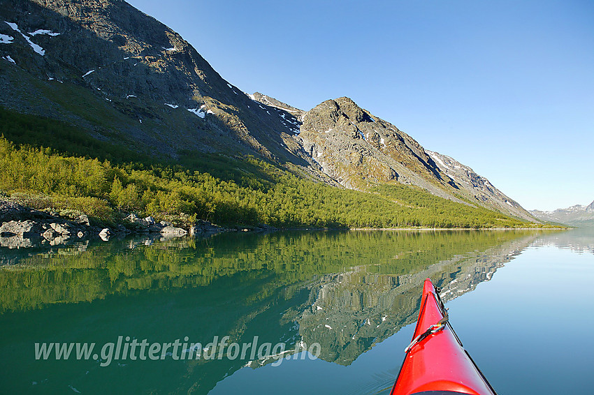 Padling langs sørbredden på Gjende. I bakgrunnen et idyllisk nes der Skarvflyåe kommer ned fra Gjendealpene. På hitsiden av neset ligger det ei flott flott strand.