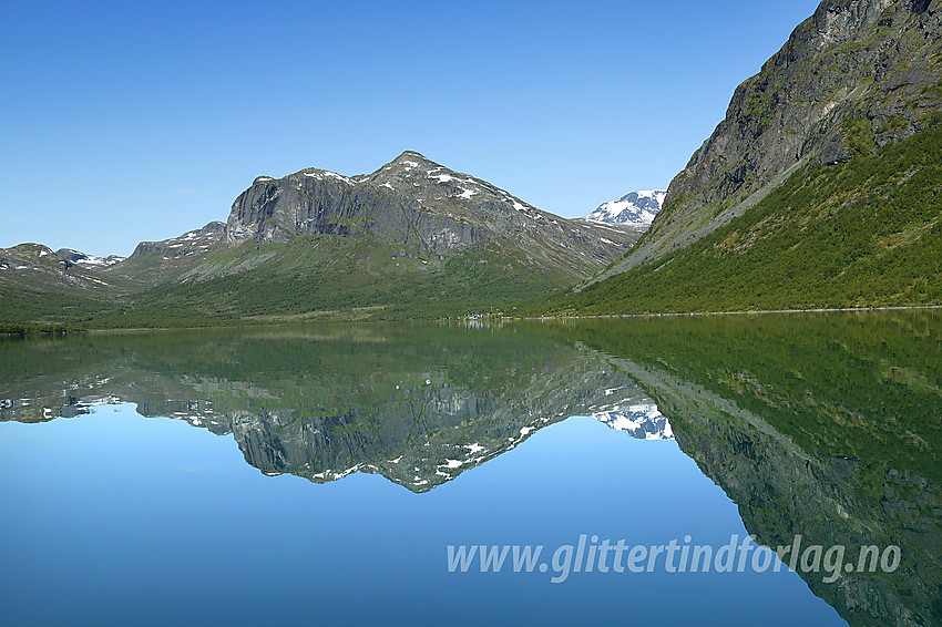 Padling på Gjende. Etter noen timer i kajakken nærmer vestenden seg omsider. Til høyre seg Gjendebu med Gjendetunga (1516 moh) bakenfor. Bak til høyre, med snø på, ses Snøholstinden (2141 moh).