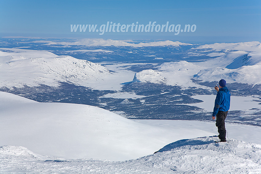 På Nautgardstinden med behov for kontakt med omverdenen. I bakgrunnen Griningsdalen og Griningsdalskampen. I det fjerne Espedalen og bl.a. Ruten (1516 moh litt til venstre for midten).