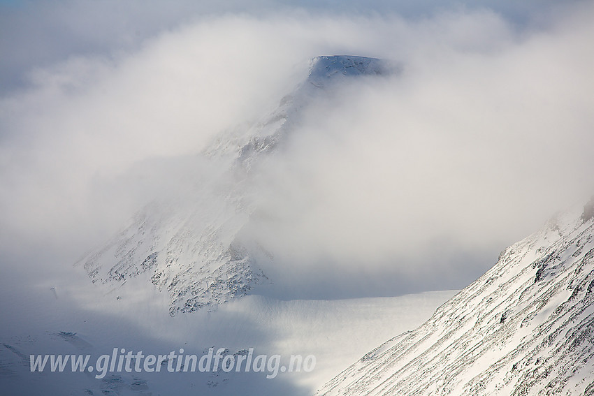 Velsfjelltinden (2157 moh) god innpakket i skyer. Her sett fra Dumhøplatået med telelinse.